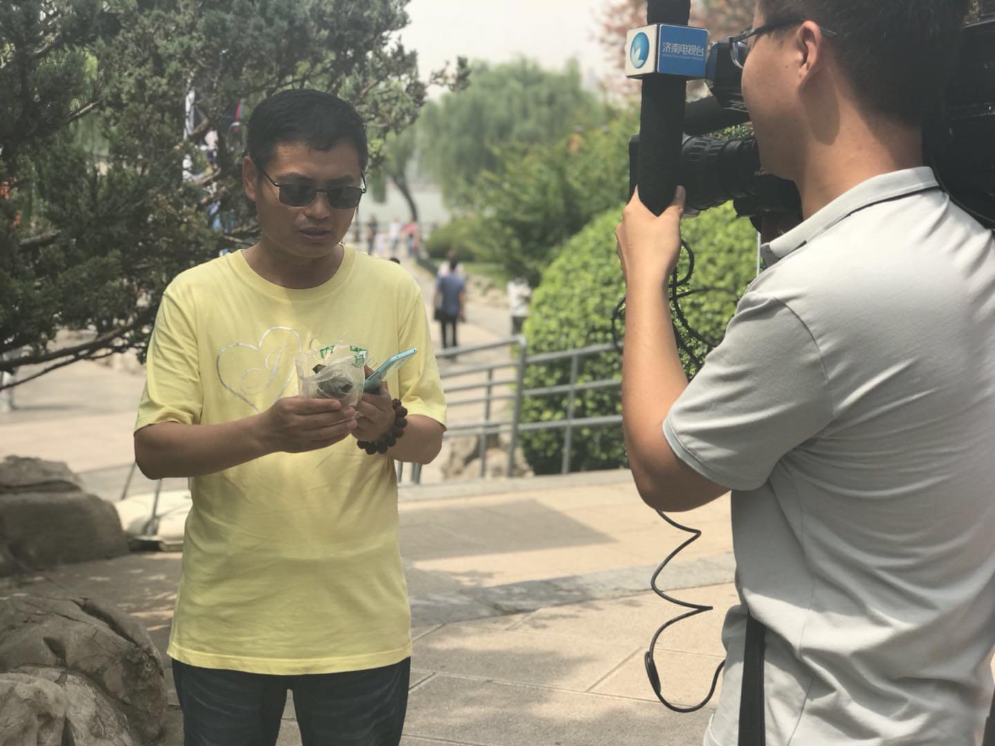 領(lǐng)到荷葉粽的市民心情激動地接受電視臺采訪